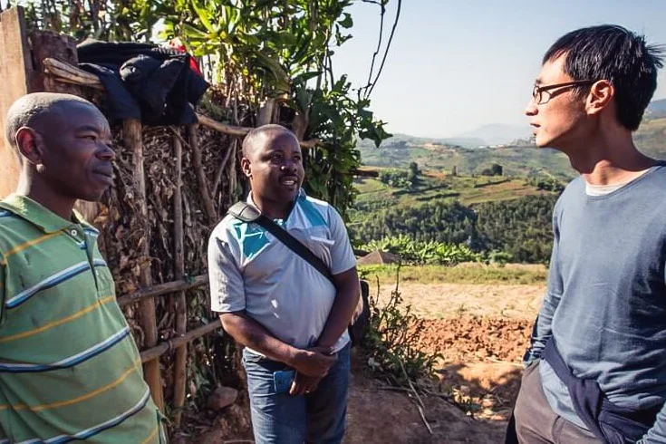 One Acre Fund founder Andrew Youn speaking with two African men outside.