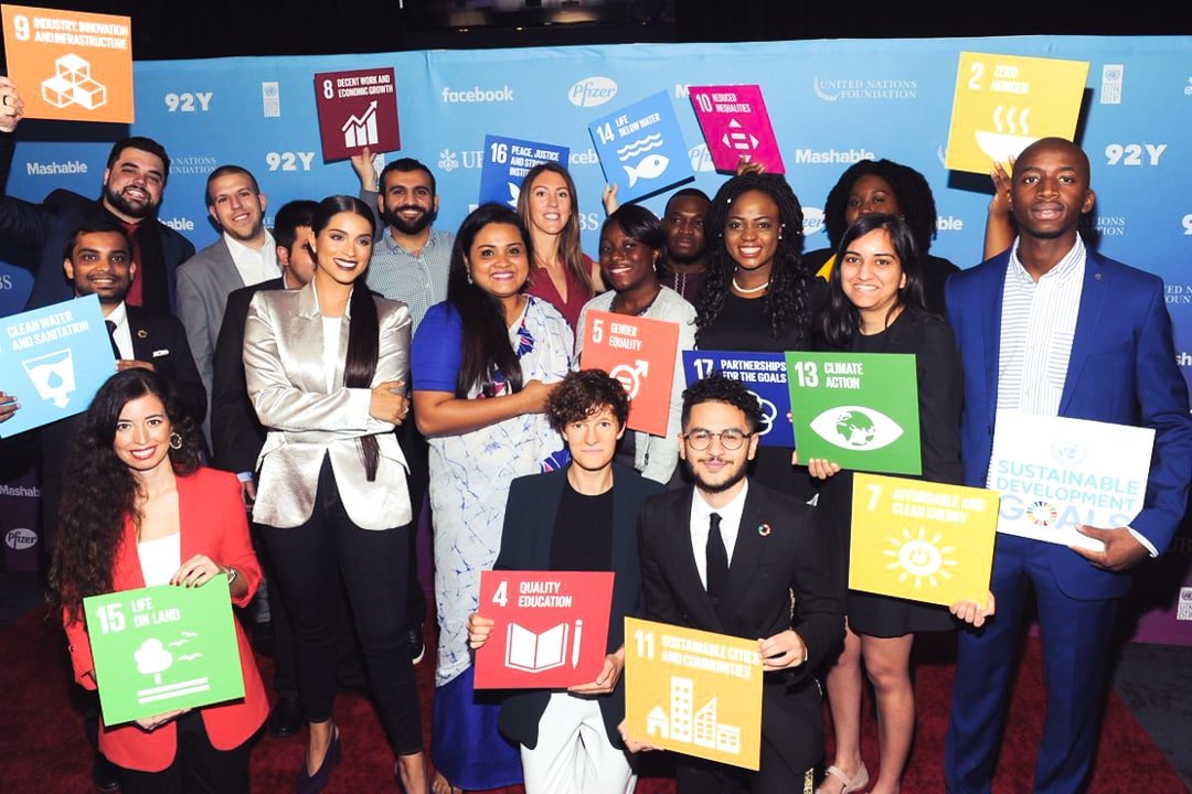 A group of male and female UN Young Leaders from around the world, holding SDG signs.