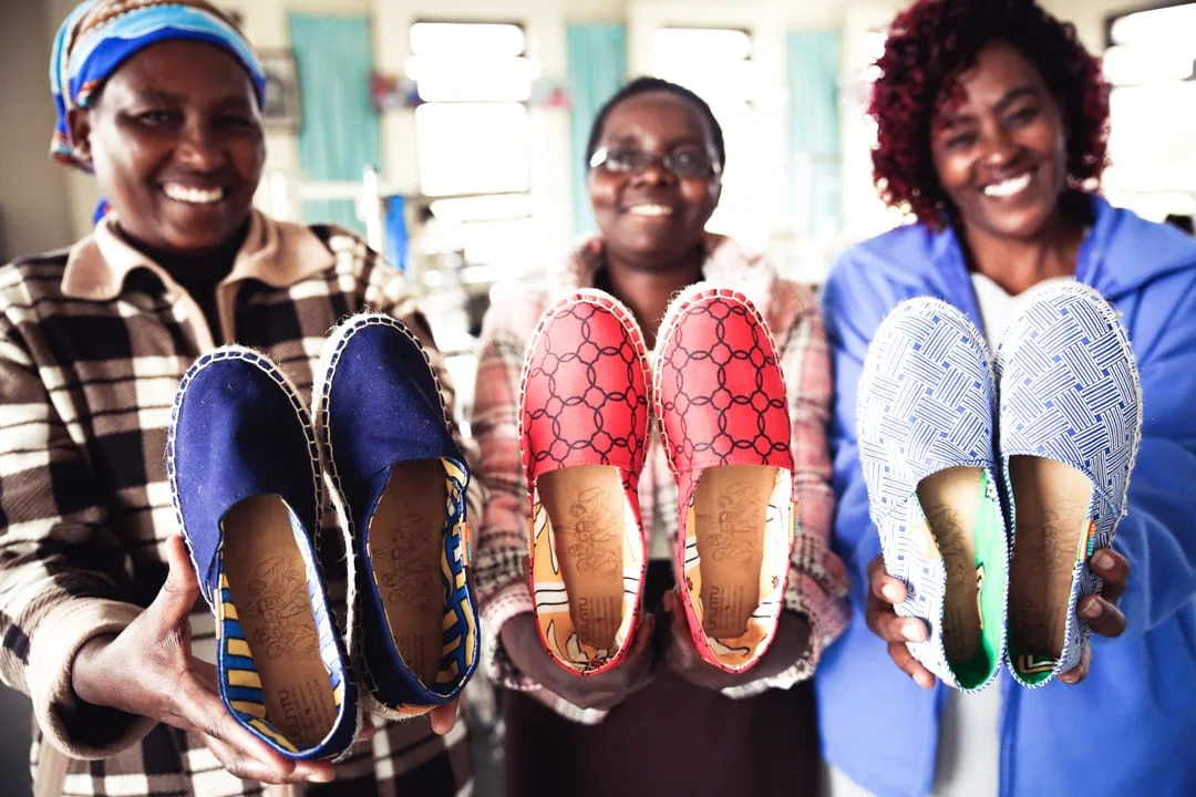 Three Kenyan Ubuntu Life Maker Mums holding pairs of the Afridrille shoes they have created.