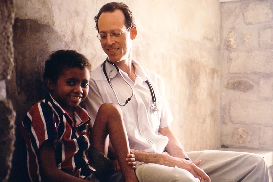 Dr. Paul Farmer smiling with a young boy in a still shot from the film Bending the Arc.