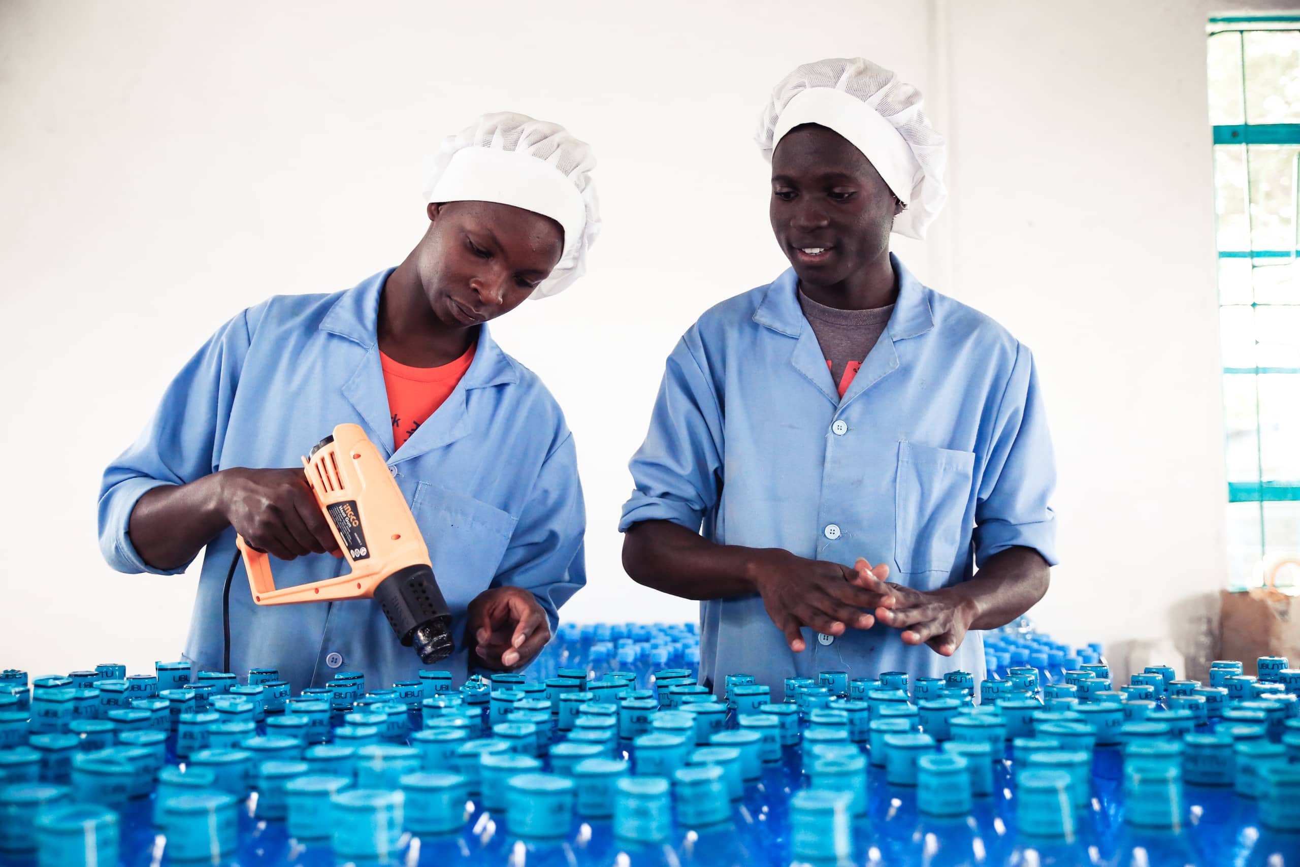 Two Kenyan men sealing plastic water bottles in an Ubuntu Life factory