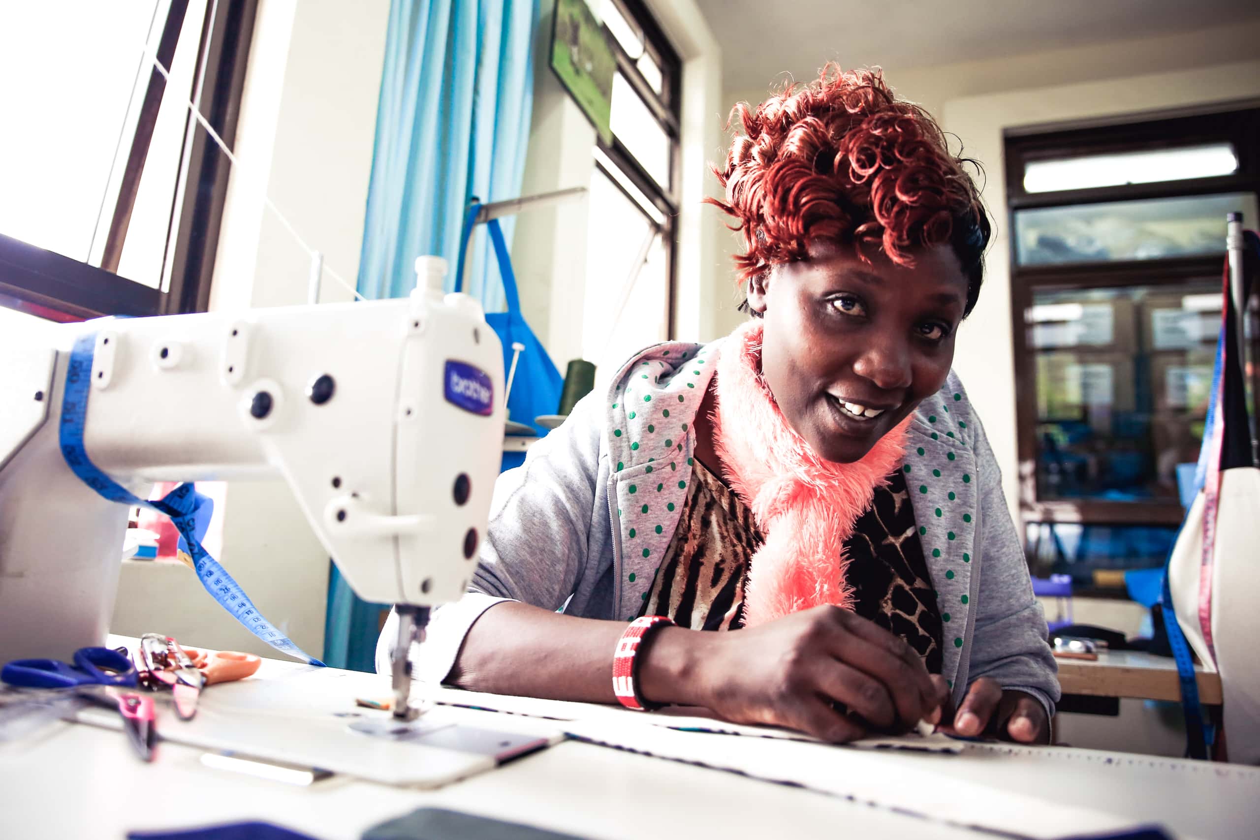 Kenyan woman looks up from a sewing machine in the Ubuntu Life factory