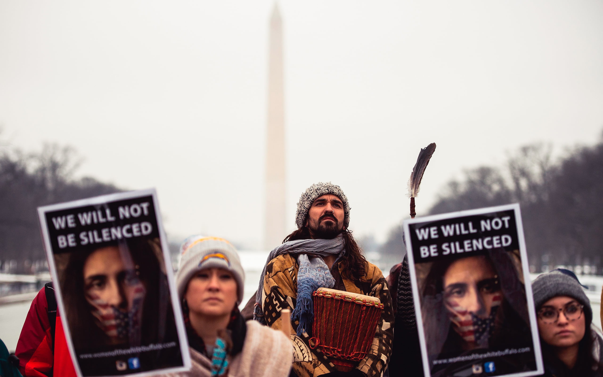 Native American men and women protesting with signs in front of the Washington Monument