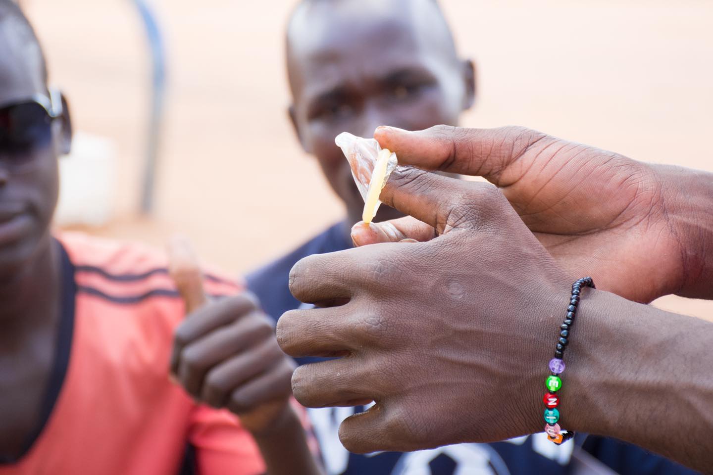 Ugandan men watching a tutorial on how to wear a condom