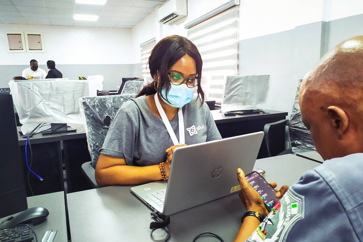 A female African doctor wearing a mask and working on a laptop.