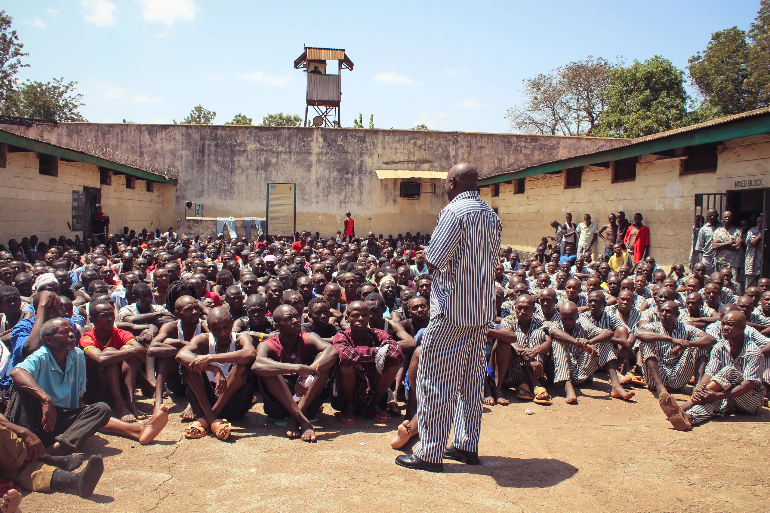 Man speaking to a crowd of male persons who are incarcerated in East Africa.