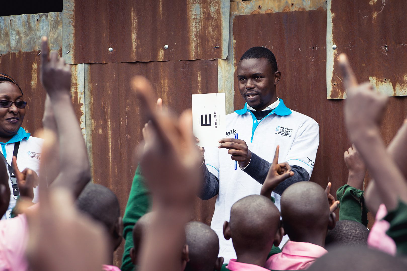 African man giving a group eye exam.