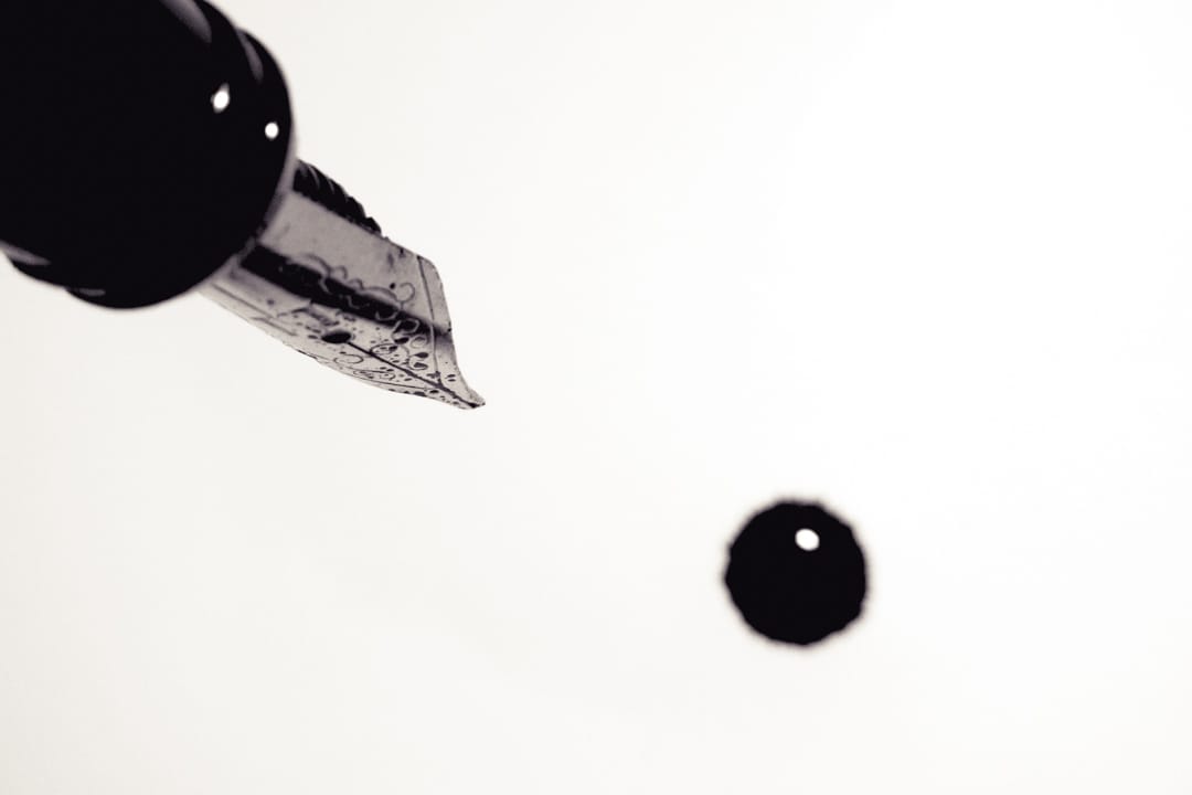 Close-up image of a fountain pen and a single blot of ink.